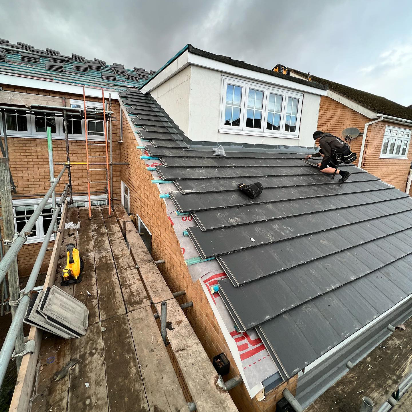 Roofer laying tiles onto a roof